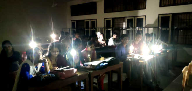 Students study in cellphone light, courtesy EVM strongroom wall